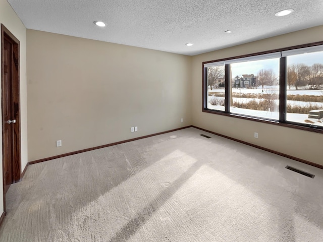 empty room featuring baseboards, visible vents, and light colored carpet