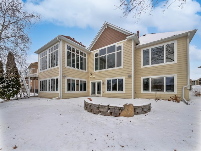 snow covered house featuring stairs