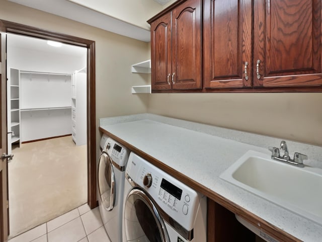 laundry area featuring cabinet space, light tile patterned floors, washer and clothes dryer, and a sink