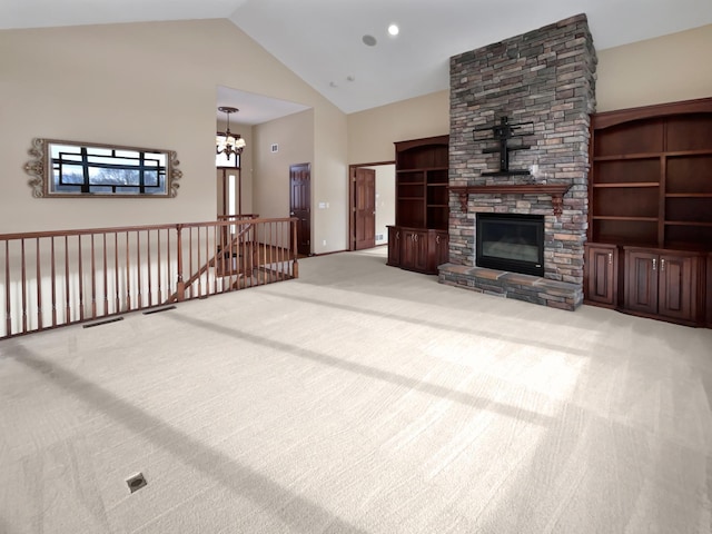 carpeted living area with high vaulted ceiling, a stone fireplace, and an inviting chandelier