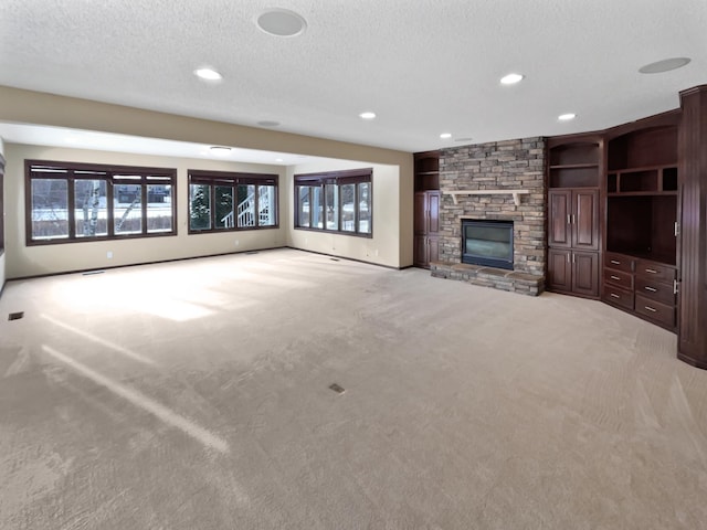 unfurnished living room with built in shelves, a fireplace, recessed lighting, light colored carpet, and a textured ceiling