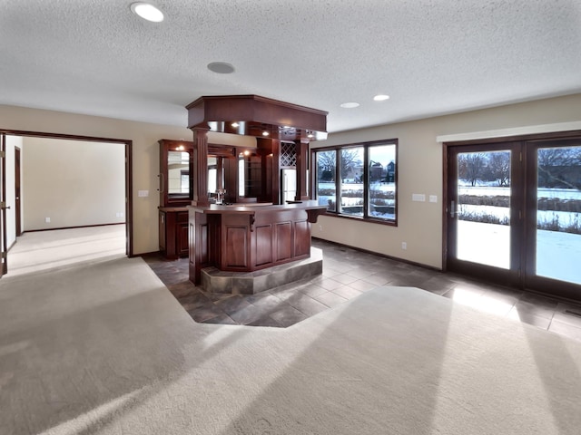 bar featuring a textured ceiling, carpet, baseboards, and tile patterned floors