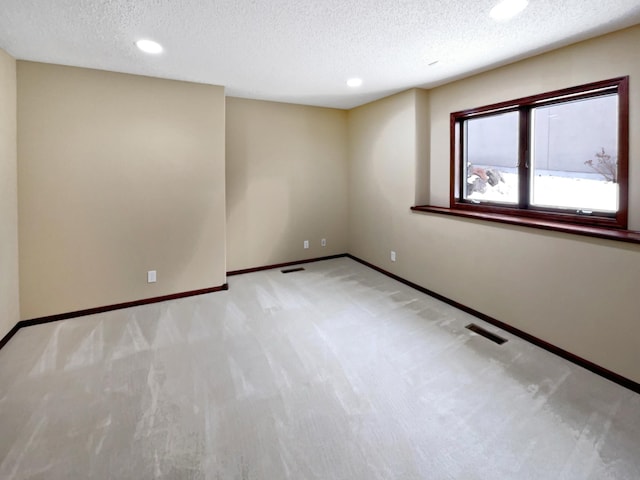 unfurnished room with light carpet, baseboards, visible vents, and a textured ceiling