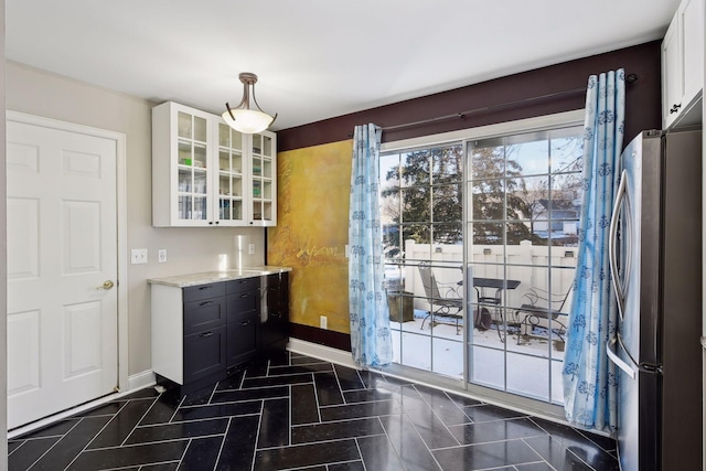 doorway to outside with baseboards and dark tile patterned floors