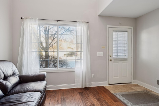 doorway with baseboards, a healthy amount of sunlight, and wood finished floors