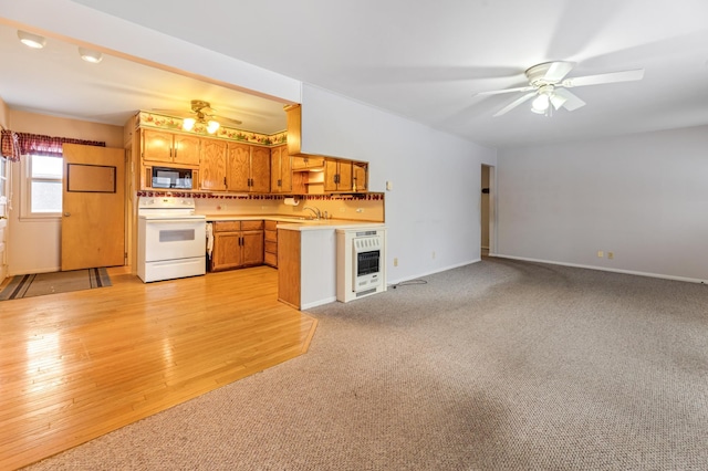 kitchen with white electric range oven, ceiling fan, light countertops, black microwave, and a sink