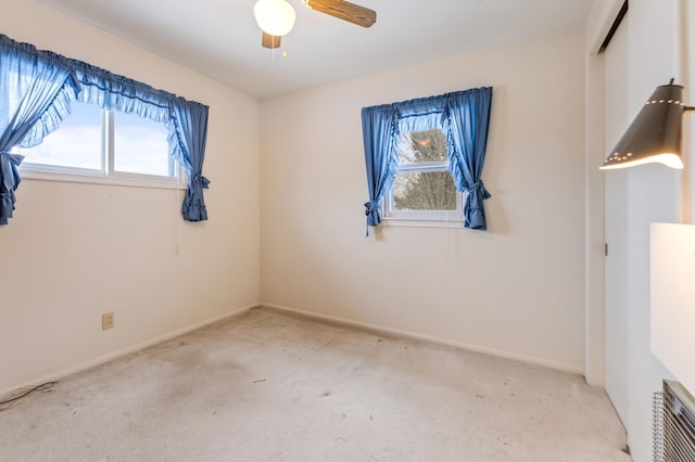 carpeted empty room with a ceiling fan and baseboards