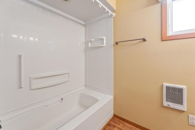 full bath with shower / washtub combination, wood finished floors, and heating unit