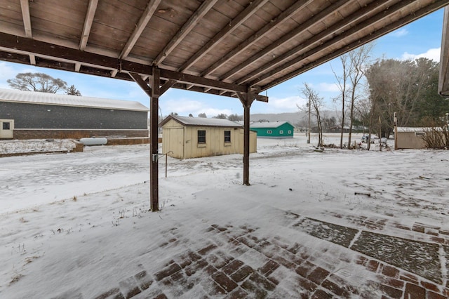 snowy yard featuring an outdoor structure and a storage shed