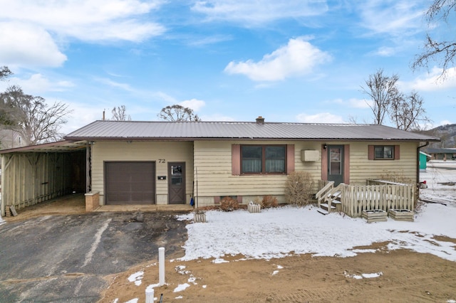 ranch-style house featuring a garage, metal roof, and driveway