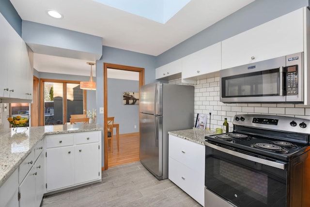 kitchen featuring stainless steel appliances, wood finish floors, white cabinetry, light stone countertops, and tasteful backsplash