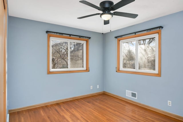 spare room with visible vents, ceiling fan, baseboards, and wood finished floors