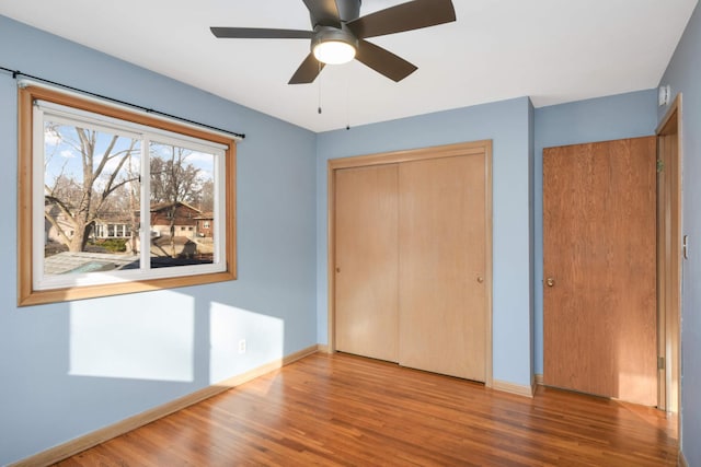 unfurnished bedroom with a ceiling fan, a closet, baseboards, and wood finished floors