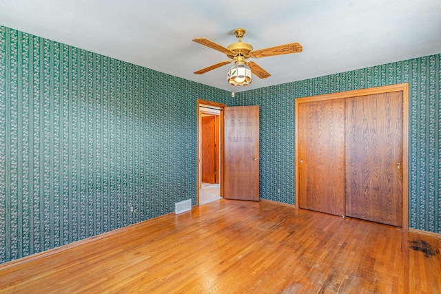 13197 132nd St W, Apple Valley, MN 55124 - unfurnished bedroom featuring wallpapered walls, wood finished floors, a closet, a ceiling fan, and baseboards