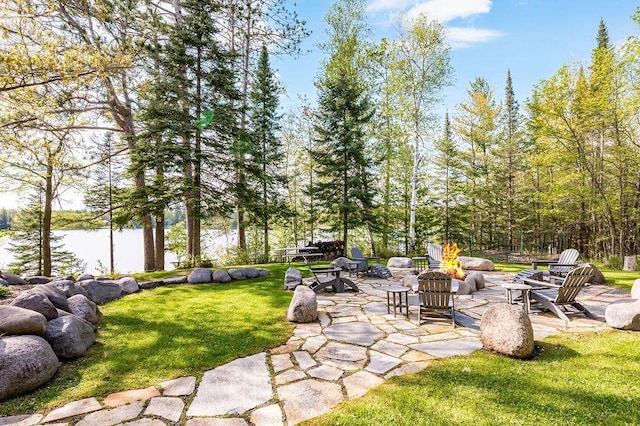 view of yard with a water view, a patio area, and an outdoor fire pit