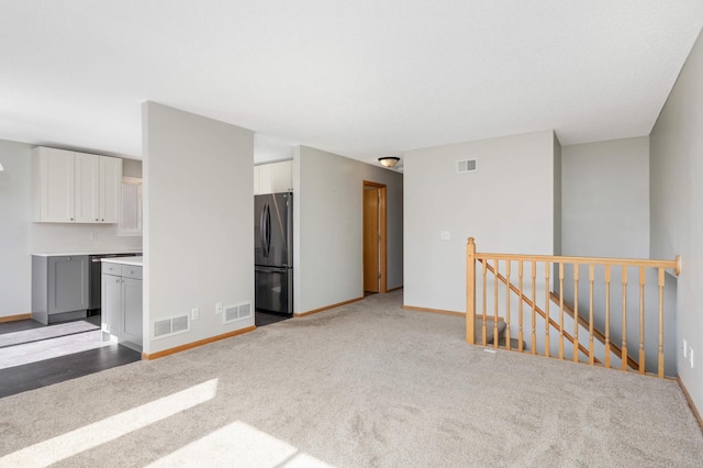 empty room with carpet, visible vents, and baseboards