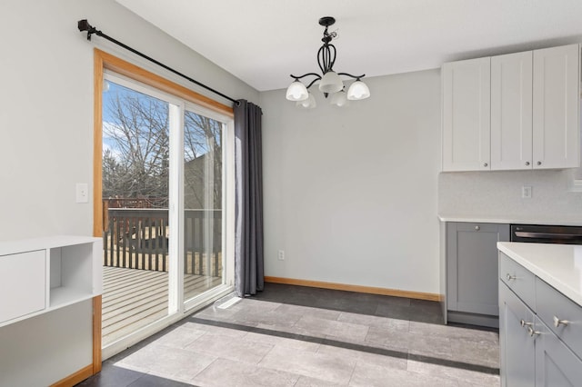 unfurnished dining area with an inviting chandelier and baseboards