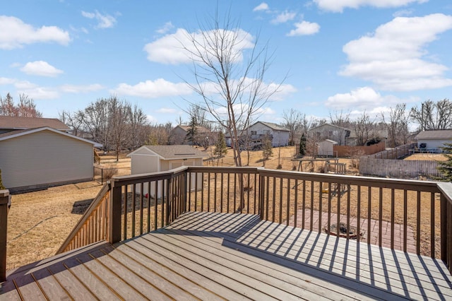 deck featuring a storage unit, an outdoor structure, fence, and a residential view