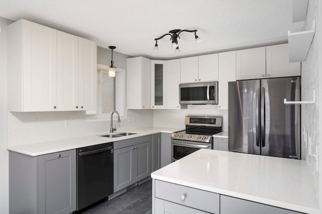 kitchen with glass insert cabinets, appliances with stainless steel finishes, hanging light fixtures, light countertops, and gray cabinetry