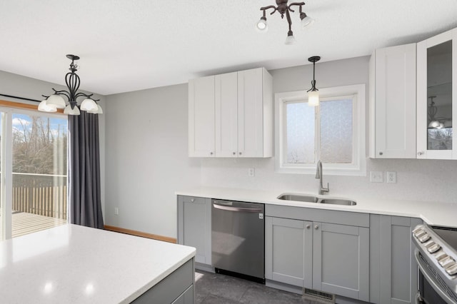 kitchen featuring glass insert cabinets, appliances with stainless steel finishes, gray cabinets, light countertops, and a sink