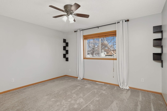 carpeted empty room with ceiling fan, a textured ceiling, and baseboards