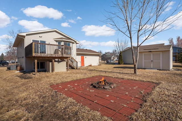 back of property featuring a fire pit, an outbuilding, stairs, a deck, and a shed