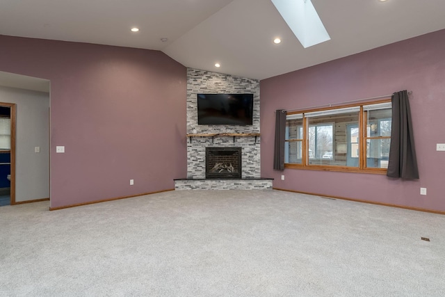 unfurnished living room featuring lofted ceiling with skylight, a fireplace, baseboards, and carpet flooring