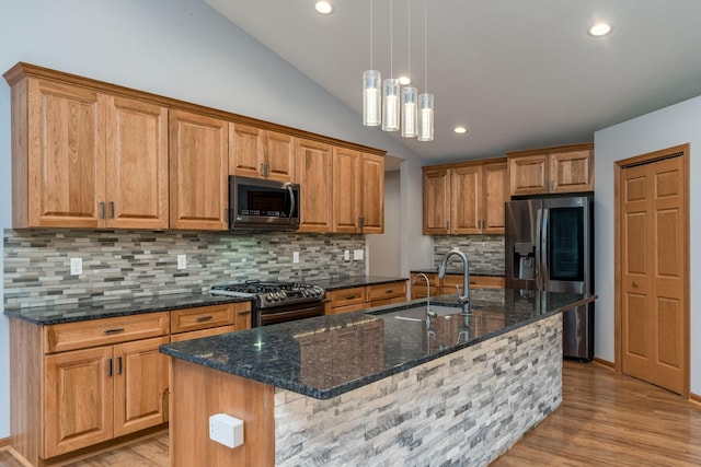 kitchen featuring stainless steel appliances, light wood-type flooring, vaulted ceiling, and a sink