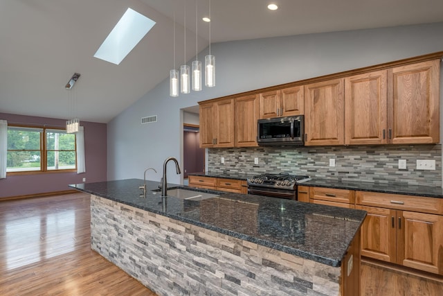 kitchen featuring stainless steel appliances, visible vents, light wood-style flooring, brown cabinetry, and a sink