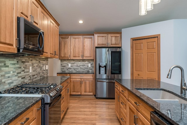 kitchen featuring light wood-type flooring, brown cabinets, a sink, and black appliances