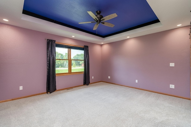 spare room featuring a tray ceiling and baseboards