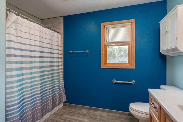 bathroom with a shower with shower curtain, baseboards, vanity, and toilet