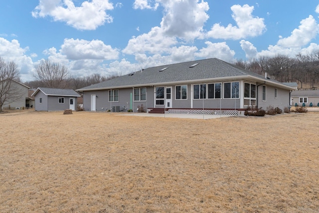 back of property with entry steps, a lawn, and a sunroom