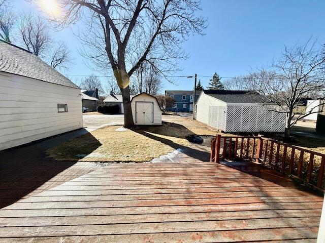 wooden terrace featuring a storage shed and an outbuilding