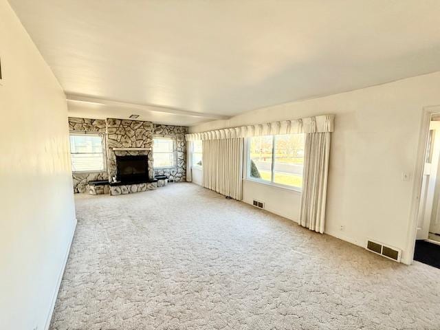 unfurnished living room featuring carpet floors, plenty of natural light, a fireplace, and visible vents