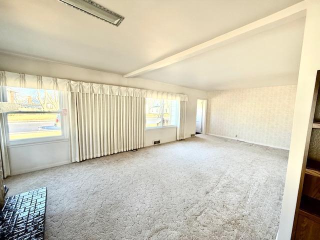 carpeted empty room with visible vents and beam ceiling