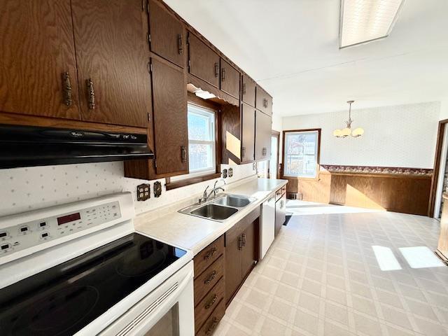 kitchen featuring extractor fan, dark brown cabinetry, white appliances, a sink, and light floors