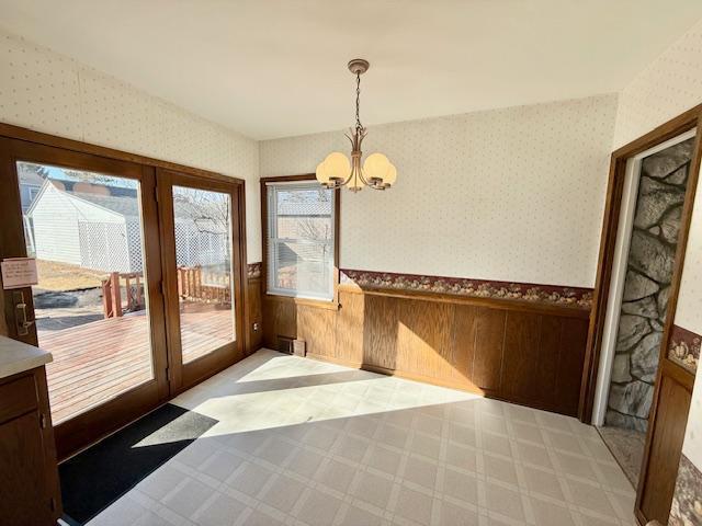 interior space featuring wainscoting, a notable chandelier, and wallpapered walls