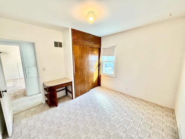 unfurnished bedroom with carpet floors, a closet, and visible vents