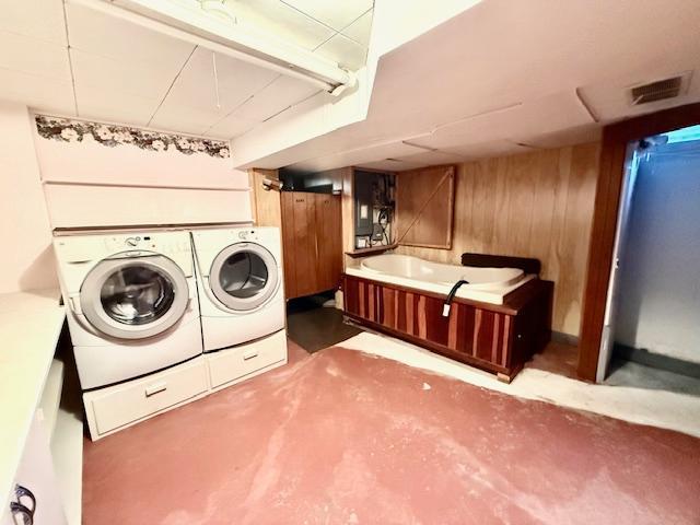 washroom with wood walls, visible vents, and washer and dryer