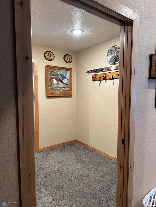 corridor featuring a textured ceiling, baseboards, and carpet flooring