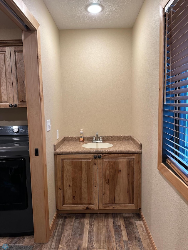 interior space with cabinet space, baseboards, dark wood finished floors, a textured ceiling, and a sink