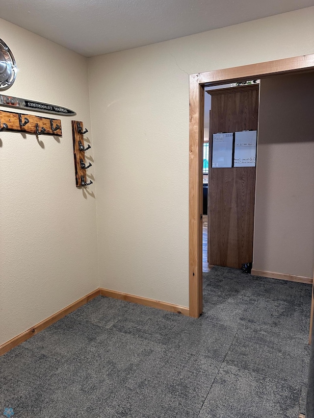 unfurnished room featuring carpet and baseboards