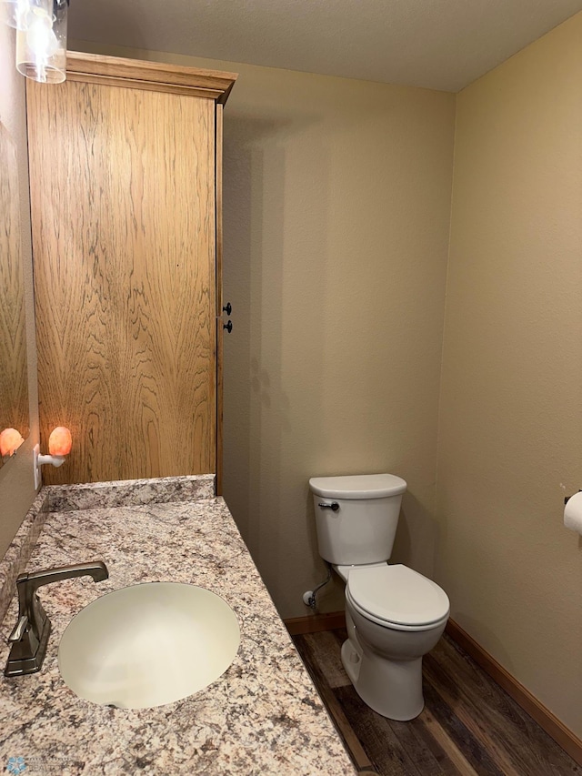 bathroom featuring vanity, wood finished floors, toilet, and baseboards