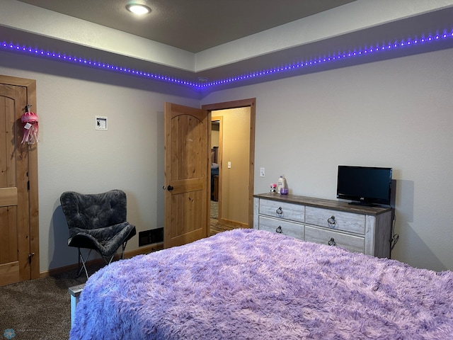 carpeted bedroom featuring a tray ceiling and baseboards