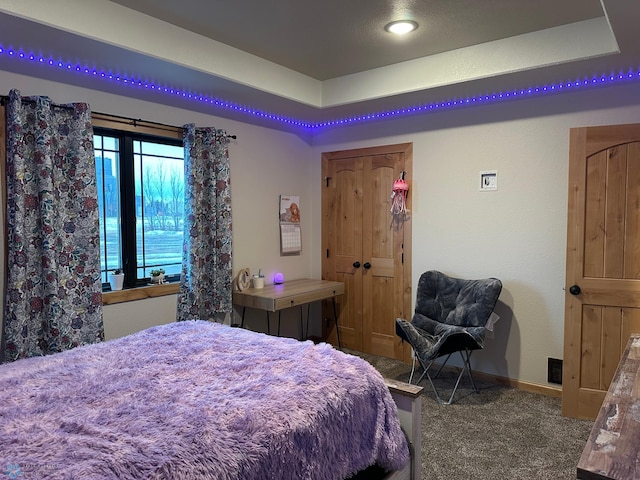 bedroom with a raised ceiling, carpet flooring, and baseboards