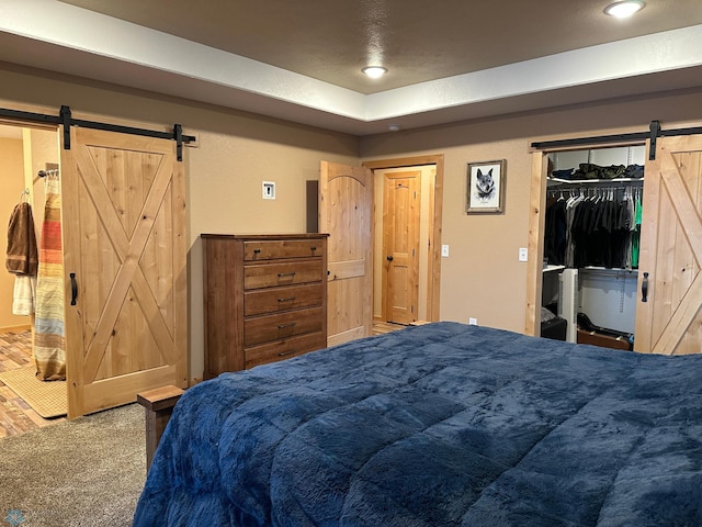 carpeted bedroom with a barn door and recessed lighting