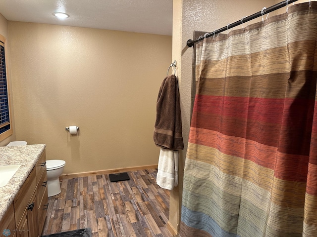 full bath featuring baseboards, a shower with shower curtain, toilet, wood finished floors, and vanity