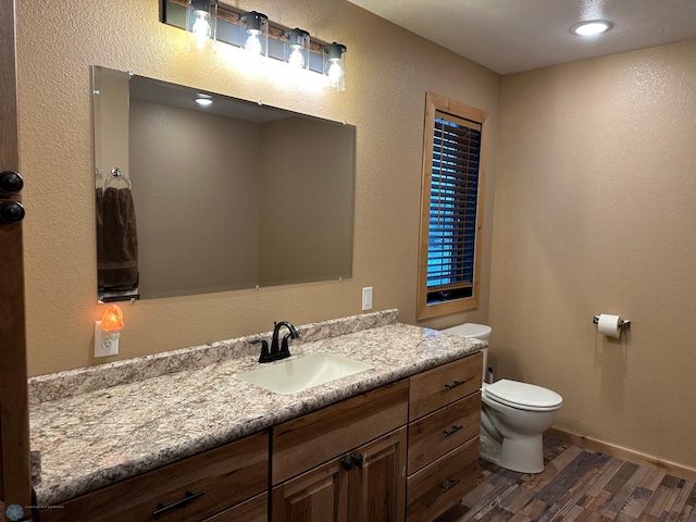 bathroom featuring a textured wall, vanity, toilet, and wood finished floors