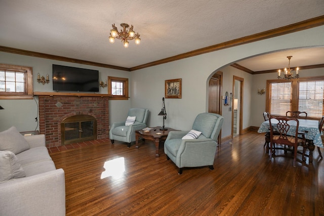 living area with a brick fireplace, arched walkways, an inviting chandelier, and wood finished floors